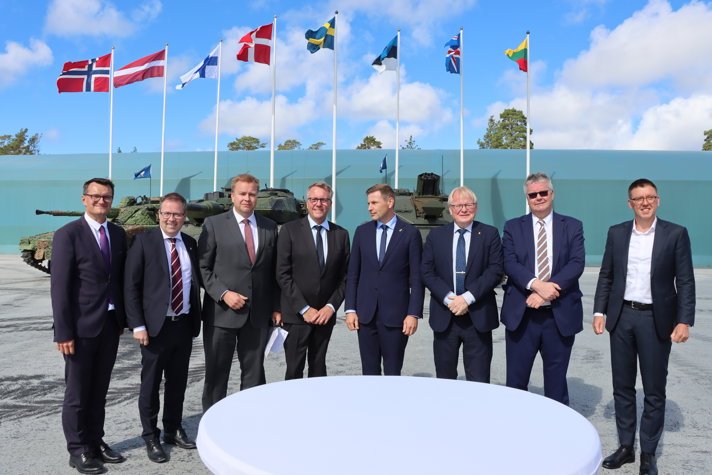 The Nordic and Baltic defence ministers are standing outside the Gotland Regiment base P 18.