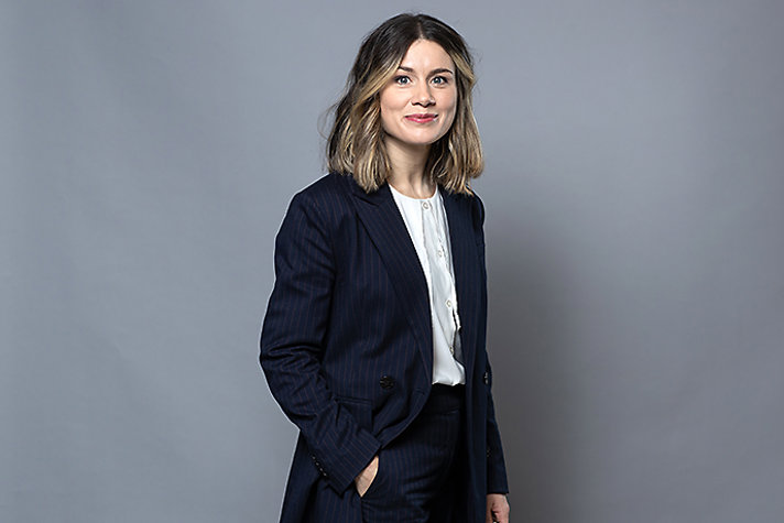 Woman in dark jacket and white blouse.