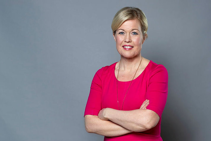 Blond woman dressed in a pink shirt.