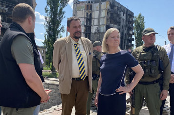 Magdalena Andersson looking out over houses that have been destroyed by Russian bombings.