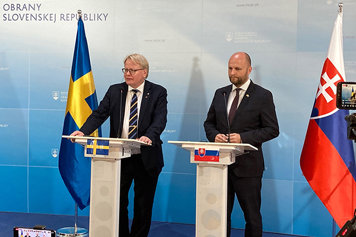 Peter Hultqvist and Jaroslav Naď stands infront of a Swedish flag and a Slovak flag