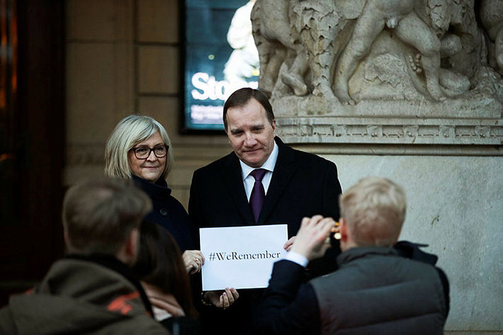 Prime minister Stefan Löfven and wife  holding a paper whereupon it is written #We Remember