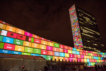 UN building lit up with UN Sustainable Development Goals.