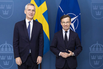 Kristersson and  Stoltenberg standing next to eachother in front of flags